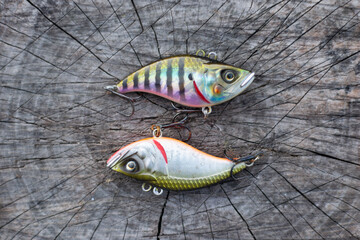 2 fishing vibrating lures for catching predatory fish, laid out on a wooden base like yin and yang