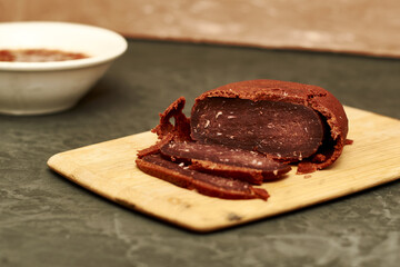 basturma on a wooden cutting board next to a plate with spices