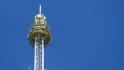 Scary unrecognizable people sitting on a free fall or high gravity tower and waiting impatiently before the big drop ride. Carnival theme park at the Kiliani Summer Festival. Acrophobia concept. 4K
