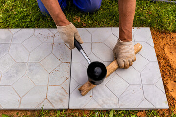 The master lays paving stones in layers. Garden brick pathway paving. Laying concrete paving slabs...