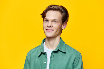 portrait of a happy guy in a green shirt on a yellow background