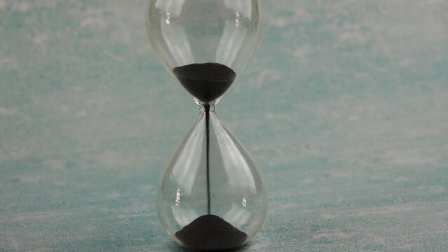 Hour glass with sand flowing through the stem