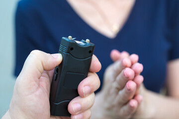 Woman asking for mercy front of a criminal with a stun gun.