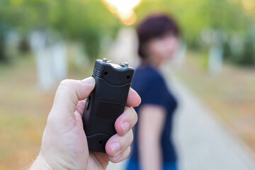Hand with electric shocker criminal catches up with the woman for the robbery.
