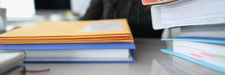 Woman sitting at table with many yellow envelopes and folders closeup
