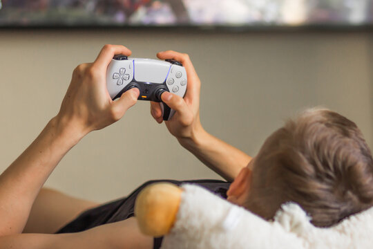 Poznan, Poland - August 2022. Man Play With Play Station 5 Dual Sense Controller In Front Of Blurred TV Screen At Home.