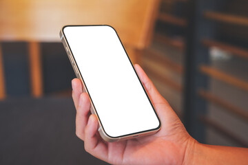 Mockup image of a woman holding mobile phone with blank desktop screen in cafe
