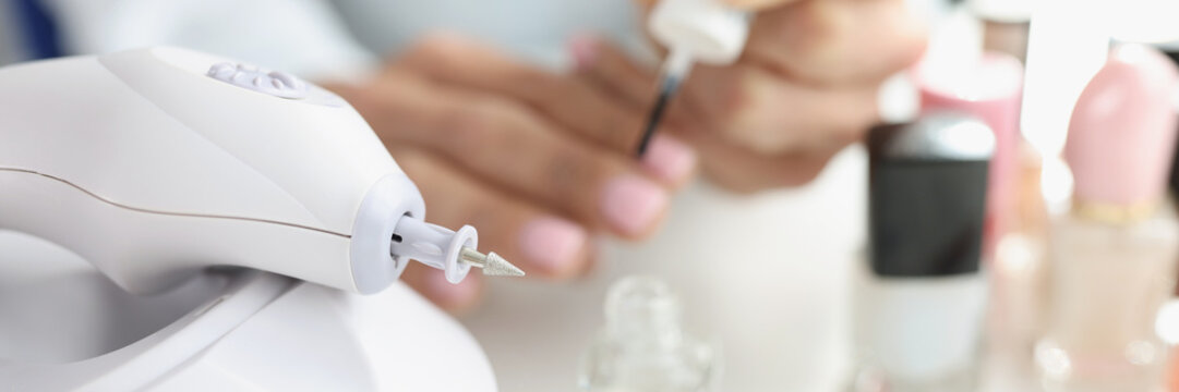 Manicurist woman hands milling decorative nails cutter in modern beauty salon