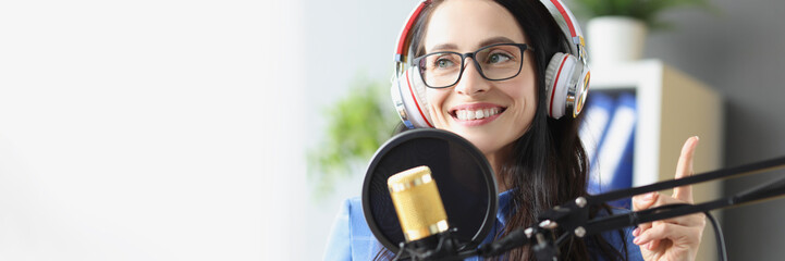 Smiling woman in headphones in front of microphone