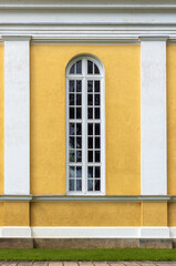 Facade of yellow wall architecture with arched window and columns