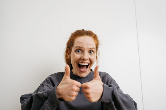 young redhead woman pointing her thumbs up happily