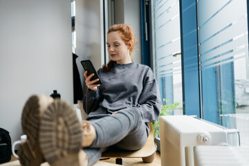 young redhead woman with cell phone takes break in office