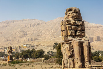 Beautiful daytime view of the Colossi of Memnon. Two large stone figures depicting a seated pharaoh. This is all that remains of the huge memorial temple of Amenhotep III.