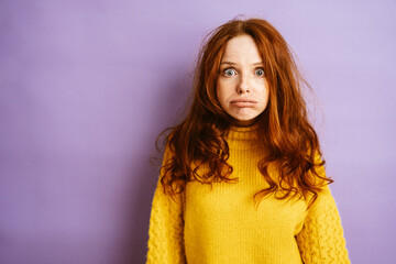 Young redhead woman looks frustrated at camera, copy space