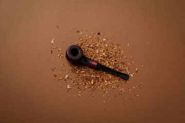 Smoking pipe with tobacco on brown background
