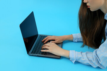 Fototapeta premium Young woman using laptop on blue background