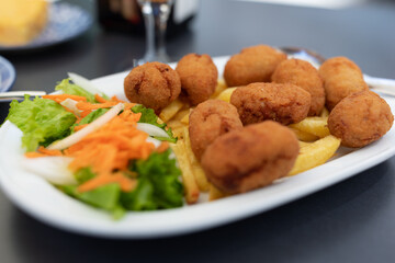 Plate with a portion of homemade croquettes of cocido, with french fries, in a bar restaurant in La Coruna, Galicia, Spain. Traditional local food