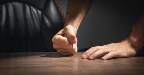 Fists of angry man beats on the table.