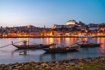 Fototapeta na wymiar Evening on the Douro River in Porto. View of the illuminated old town. Boats in the foreground. Portugal