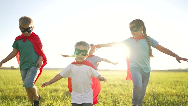 Happy family. Children dressed as superheroes play in the park. Superhero teamwork. Strong children dream of victory. Children are superheroes winners. Family game in nature. Superheroes in red capes