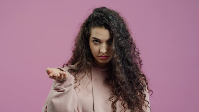 Slow motion portrait of attractive young woman twisting finger at temple showing are you crazy gesture standing against pink color background