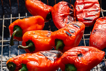 Grilling Process of preparing red bell pepper on barbecue bbq grill. Flaming fire, ember charcoal and smoke. Close up Whole street food picnic vegetables   organic.