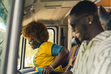 Ethnic dark-skinned straight couple having a summer road trip in a camping van, driving, talking and laughing heartily inside their vehicle. High quality photo - Powered by Adobe