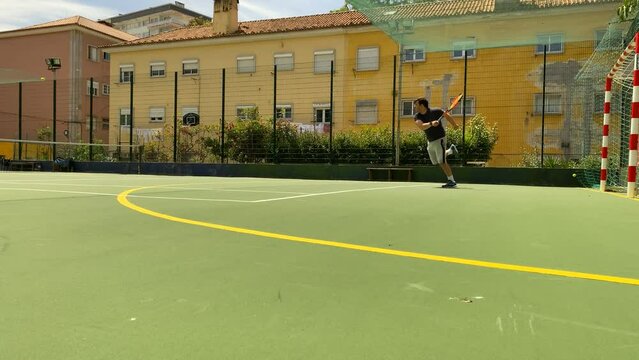 Professional tennis player hitting server in slowmotion on hard court. Fit young man in sportswear playing tennis on hard court on a sunny day.