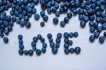 Love word Fresh blueberry Freshly picked Juicy fresh blueberries Bilberry white wood food Background. antioxidant. Concept healthy eating nutrition fruit  top view Valentine's day card.