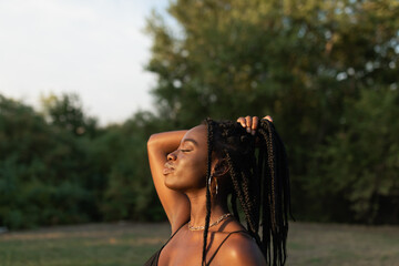 Side view of a young black female holding her braids with her hand in a ponytail with closed eyes...