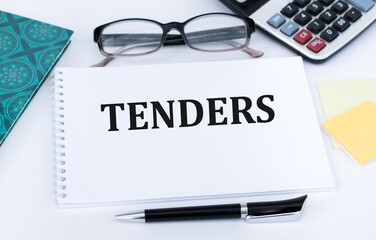 TENDERS text on notepad on the table next to glasses, calculator, pen. Business concept