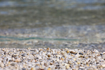 Small pebble stones on sea beach with transparent water. Natural background for summer vacation