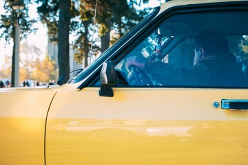 Side view of a man driving a shiny yellow taxi