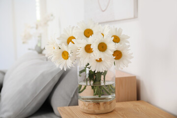 Bouquet of beautiful daisy flowers on wooden table in bedroom