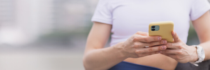 Young brunette Woman using mobile phone app before running in park. Active sporty caucasian female...