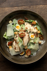 fresh caesar salad in bowl on wood background