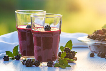 blackberry banana smoothies juice a tasty healthy drink in a glass, drink the morning on white wooden background blurred green natural sun Healthy.