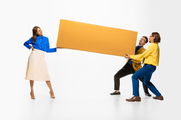 Young men carrying giant cardboard box isolated over white studio background. Woman helping. Moving...