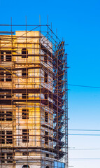 site scaffolding Apartment building under construction on a sunny day Multi-storey residential wooden structure street tlong exposure car