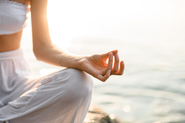 Close-up hand of caucasian woman meditating in lotus pose on the beach.