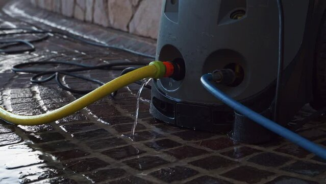 The yellow water hose leaks at the connection point to the High pressure washer for washing the machine. Leakage at the junction of water devices. Tools for home car washing.