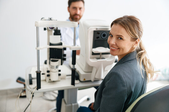 Smiling woman patient awaits a vision test at opticians shop or ophthalmology clinic