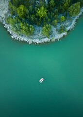 Beautiful landscape of a blue lake with an angler in a boat, bird's eye view, top view. Angler in a...