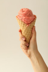 Woman holding waffle cone with delicious pink ice cream on white background, closeup