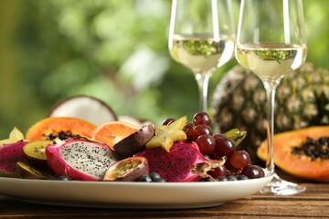 Delicious exotic fruits and wine on wooden table