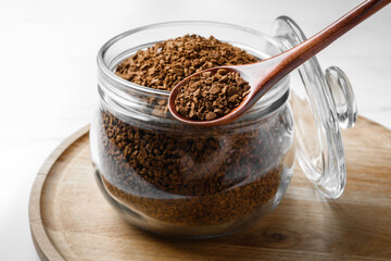 Jar of instant coffee and spoon on white table, closeup