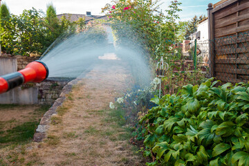watering the lawn in garden dry and dead. watering Landscaped Formal Garden from a watering hose....