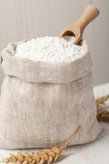 Wheat flour and spikelets on white table, closeup
