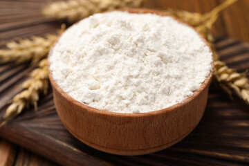 Fototapeta na wymiar Bowl of organic wheat flour on wooden table, closeup