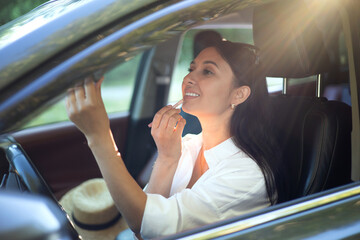 A young beautiful female driver does makeup sits behind the wheel of her car. A modern lady. A trip, a journey. Lifestyle